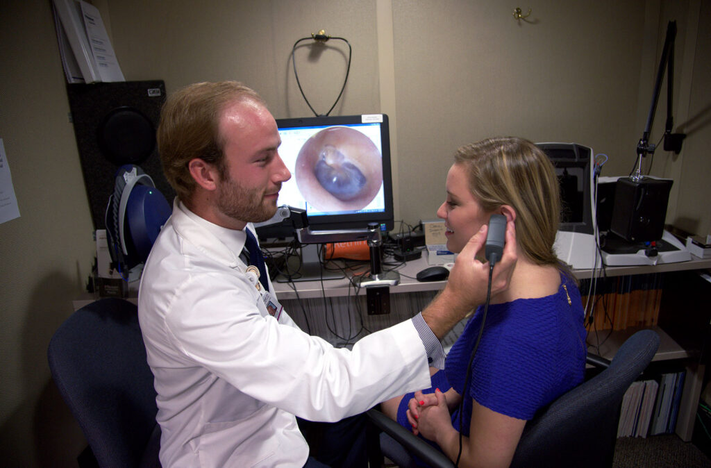 Audiology students Adam Voss and Anna Cate Clayman ( purple / shirt ) examining ear.